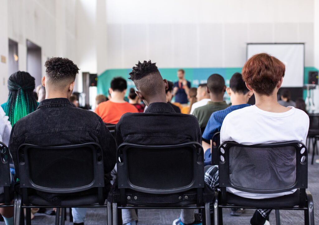Multicultural college students sitting in the back of a classroom.