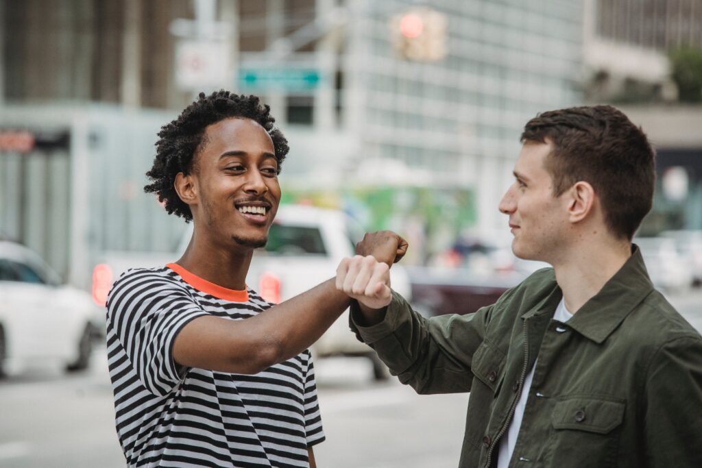 Two friends bumping fists on a city street