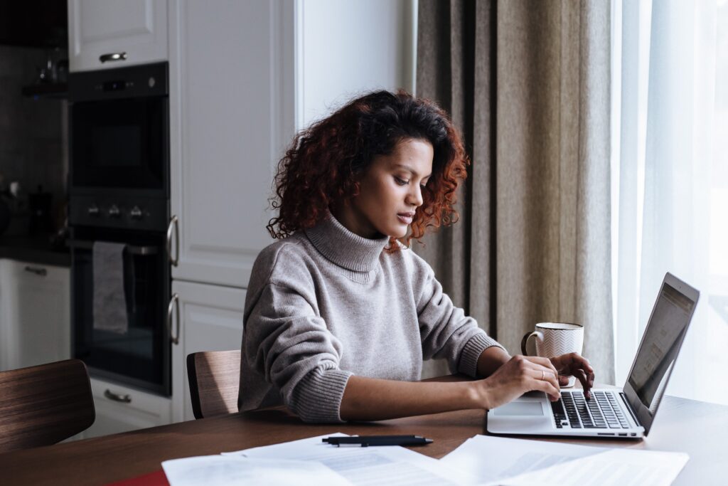 A Black woman who is working on her computer at home, exemplifying the term, "focus on your goals."