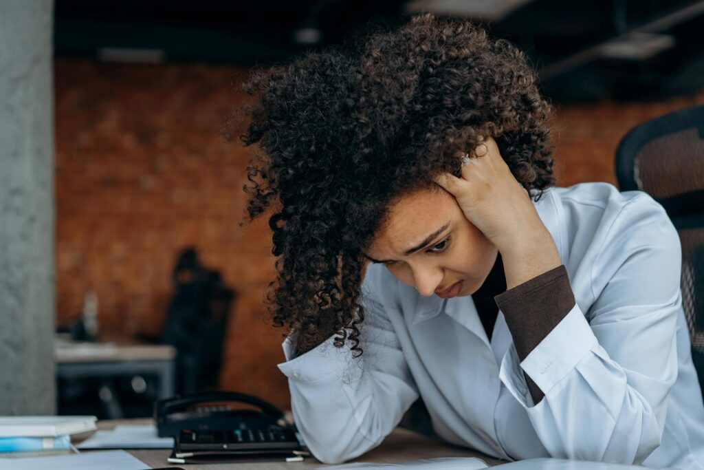 A Black woman at her day job, frustrated at her desk.