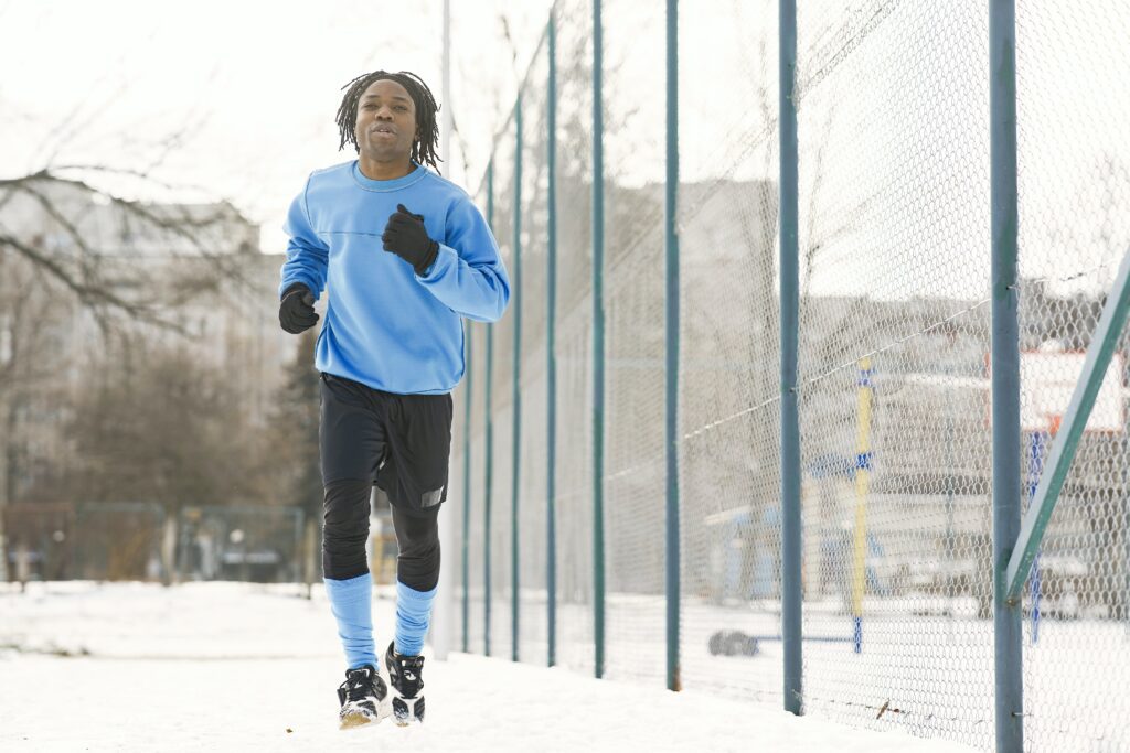 A young Black man staying consistent with his fitness goals by jogging in the snow.